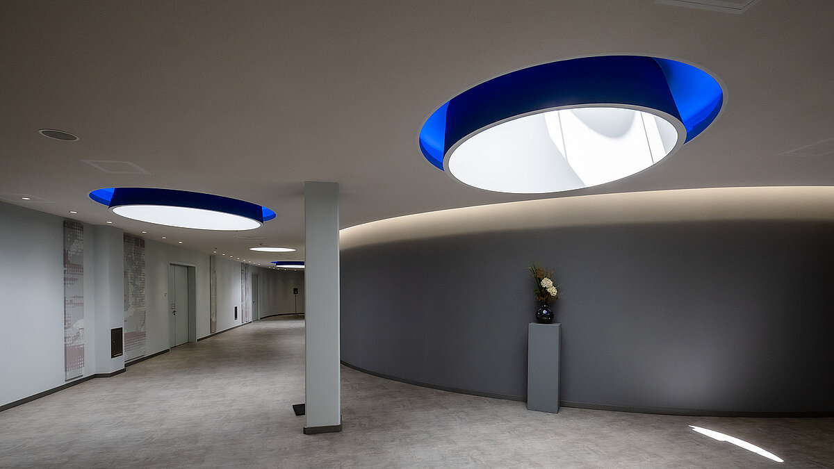 Modern hallway in the Vogel Convention Center in Würzburg with circular skylights and blue accents.