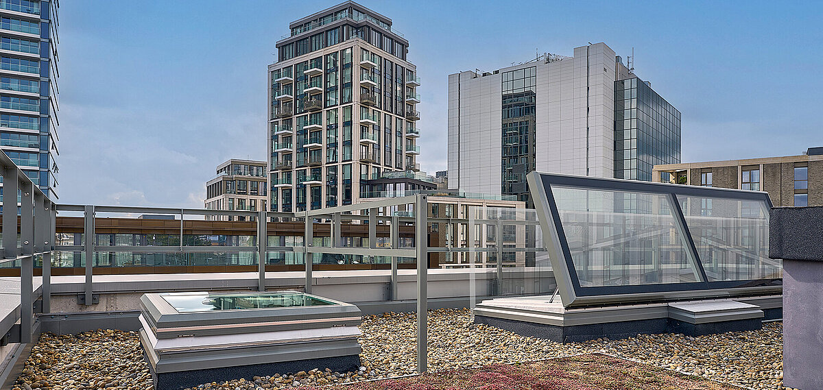 Rooftop of Mulberry Academy London featuring LAMILUX daylight systems, gravel covering, and a view of surrounding modern buildings.