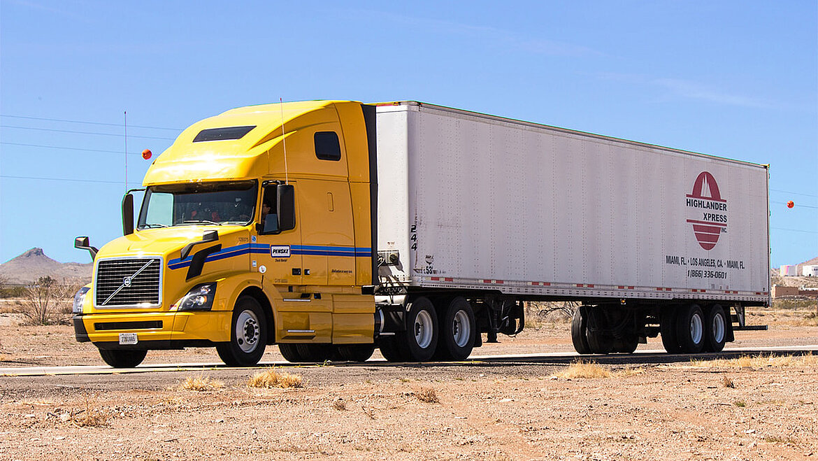 Yellow semi-truck on a gravel surface