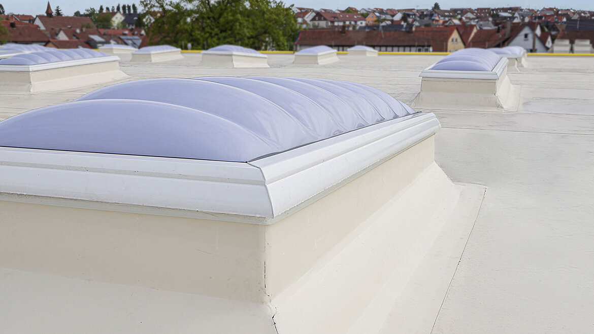 Several F100 W skylights on a flat roof overlooking a cityscape