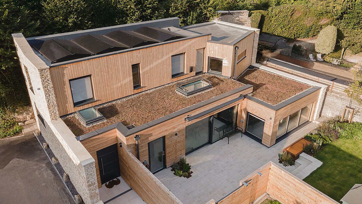 Modern villa with LAMILUX flat roof windows, natural stone facade and spacious terrace