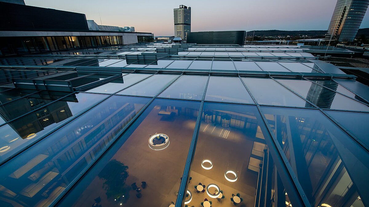 Glass roof of the FGS Campus at dusk, showing the interior with modern lights and furniture.