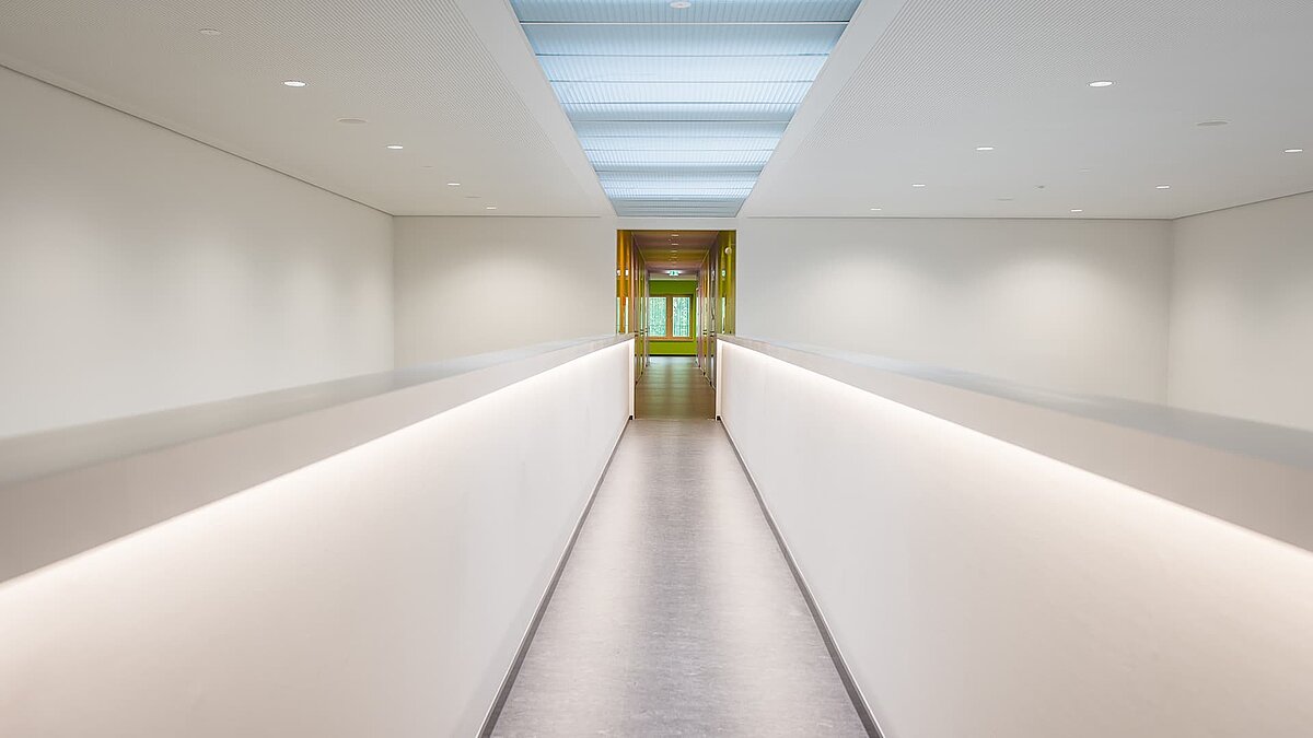 Modern-designed corridor at Markgraf-Georg-Friedrich-Gymnasium in Kulmbach featuring flat roof windows and indirect lighting.