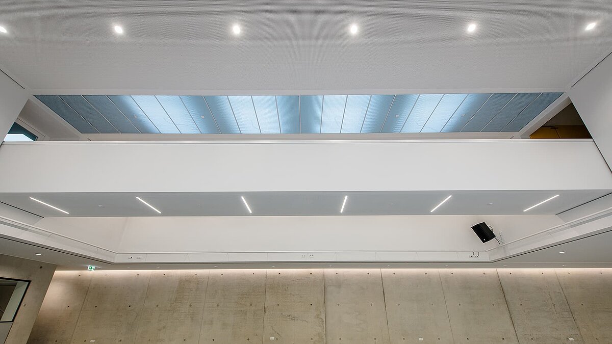 Interior view of the Markgraf-Georg-Friedrich-Gymnasium in Kulmbach featuring large flat roof windows allowing natural light into the space.