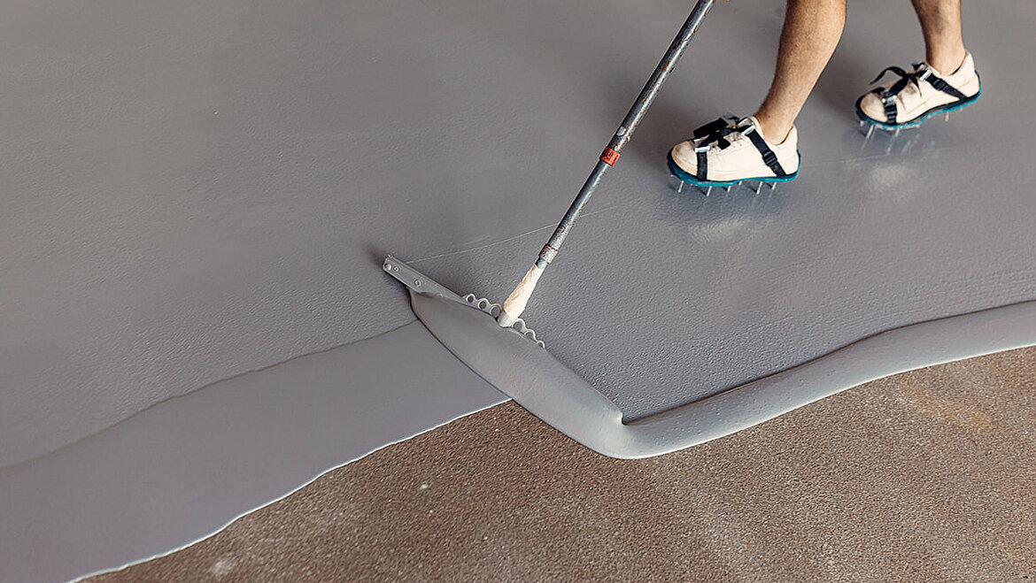 Construction workers applying epoxy resin in an industrial hall