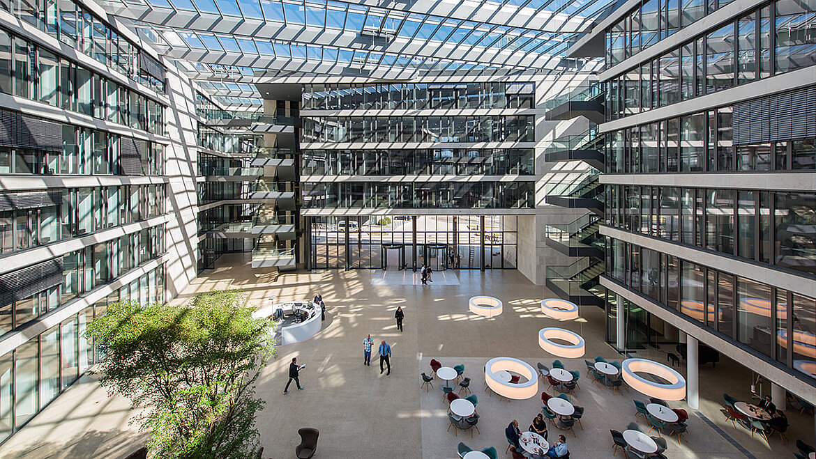 Large glazed atrium of a modern office building with glass roof and abundant daylight.