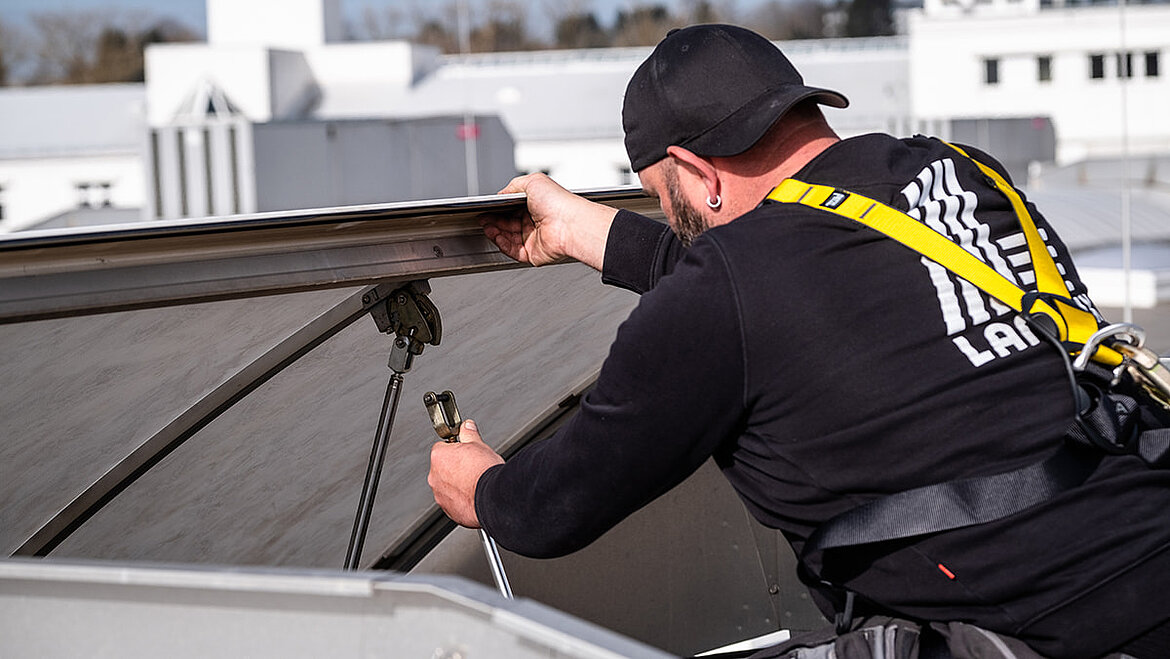 Workers wearing safety equipment during the energy-efficient renovation of a flat roof skylight strip