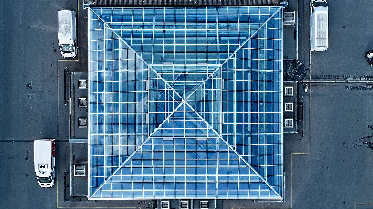 Aerial view of a square glass roof with steel frame on a flat roof building