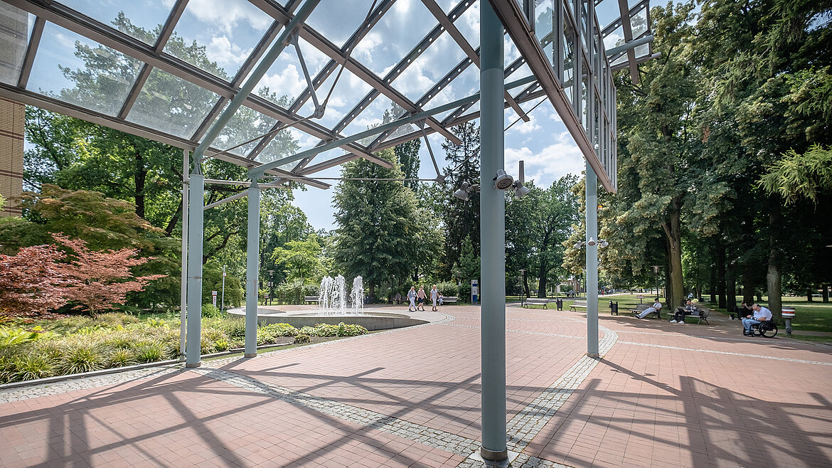 Covered outdoor area with delicate steel and glass construction in the park.