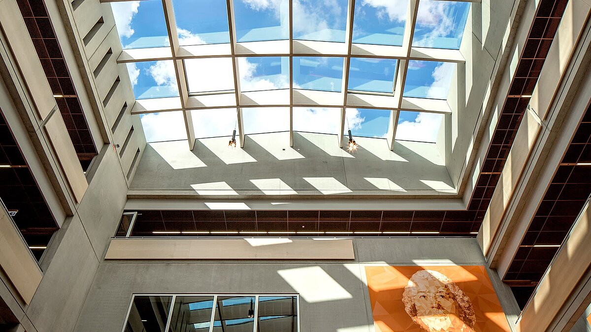 View of PR60 Passive House glass roofs by LAMILUX at Willibald-Gluck-Gymnasium in Neumarkt with blue sky and clouds.