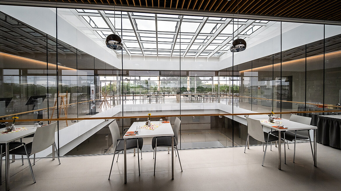 Spacious interior with glass roof and modern furnishings in an office building.