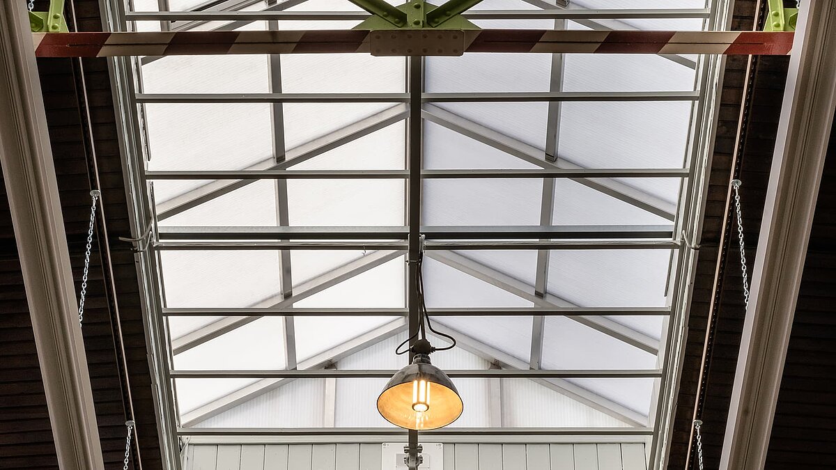 Detailed view of a modern skylight in the Zündmagnet event hall in Wurzen with steel beams and a central hanging light.