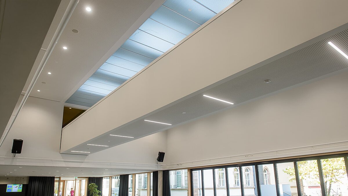Interior view of the auditorium at Markgraf-Georg-Friedrich-Gymnasium in Kulmbach featuring flat roof windows and modern lighting.