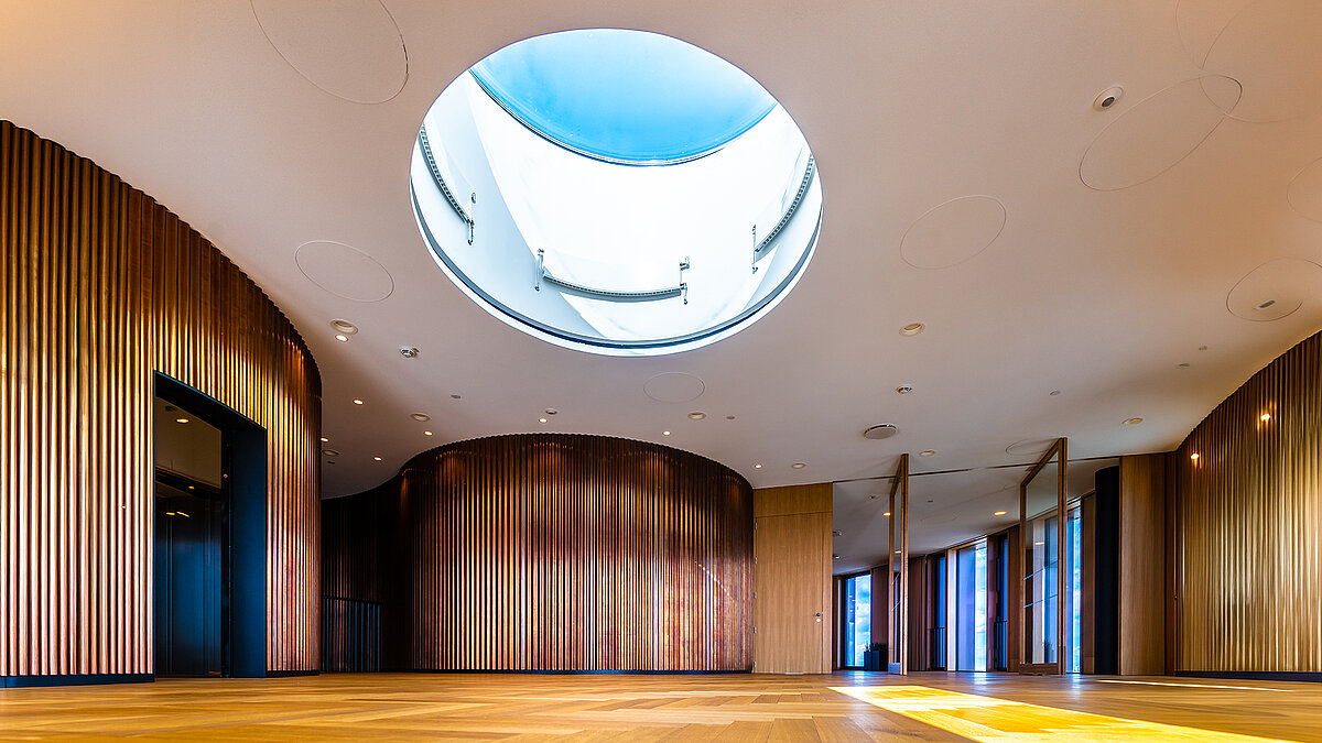 Modern interior with curved wooden paneling and large circular skylight