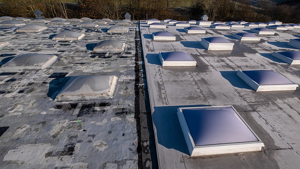 Flat roof with multiple skylights and ventilation openings under blue sky