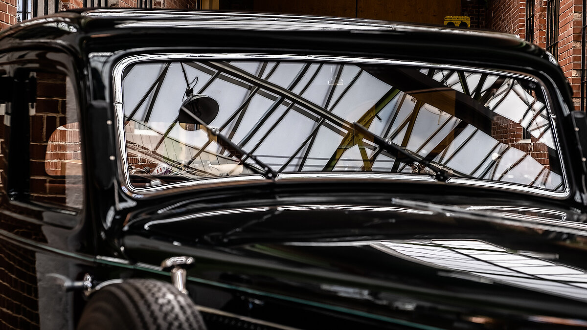 Close-up of a classic vintage car in the Zündmagnet event hall in Wurzen with the glass roof and industrial ambience in the windscreen.