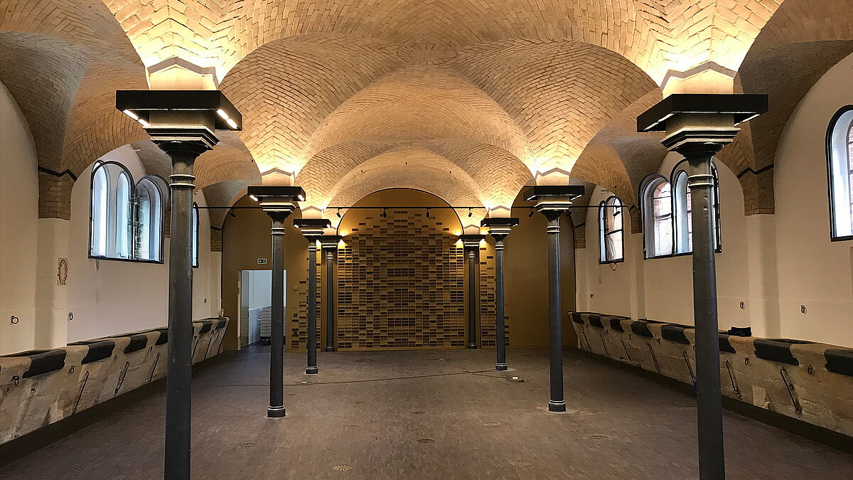 Historic interior of Leibniz University Hannover with brick vaulted ceiling, cast-iron columns, and arched windows.