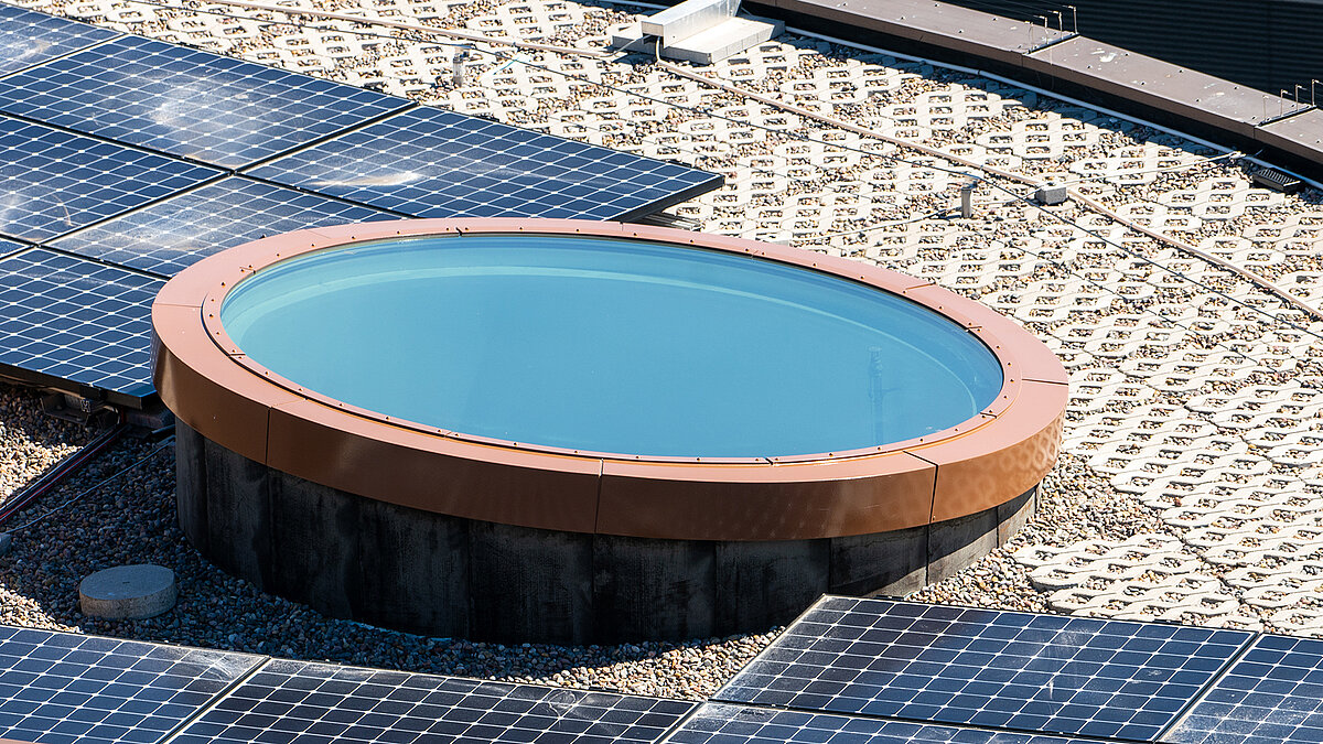 Circular skylight with glass cover on flat roof with gravel surface