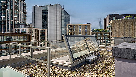 LAMILUX flat roof access on the rooftop of Mulberry Academy London, surrounded by gravel covering and modern architecture, with The Shard skyscraper visible in the background.