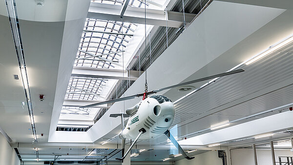 Ein Flugzeug, dass von der Decke hängt im Vordergrund vor einem Lichtband