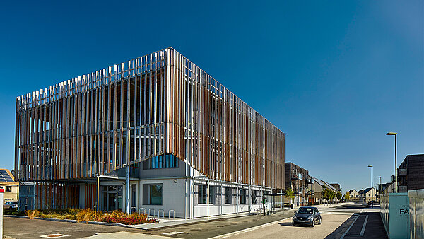 Modern office building with striking wooden facade and vertical slats under blue sky