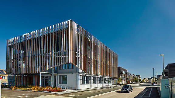 Modern office building with striking wooden facade and vertical slats under blue sky