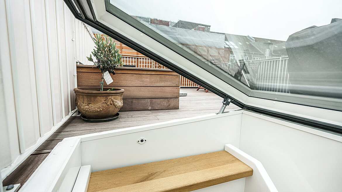 Open flat roof exit with glass cover and plants on the flat roof