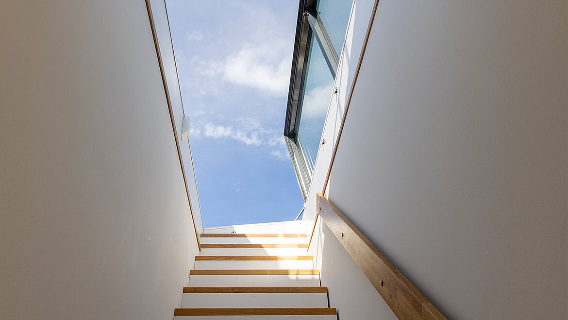 Treppenhaus mit geöffnetem LAMILUX Flachdach Ausstieg und Blick in den Himmel