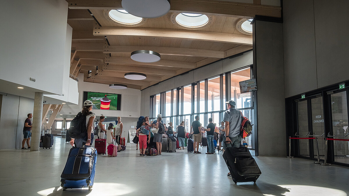 Modern harbour terminal Norderney with light wood design, round flat roof windows and waiting travellers.