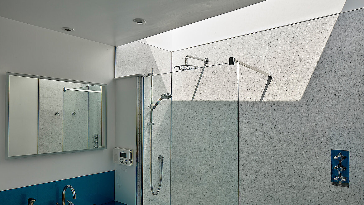 Modern bathroom with large shower and natural daylight entering through a slanted skylight.
