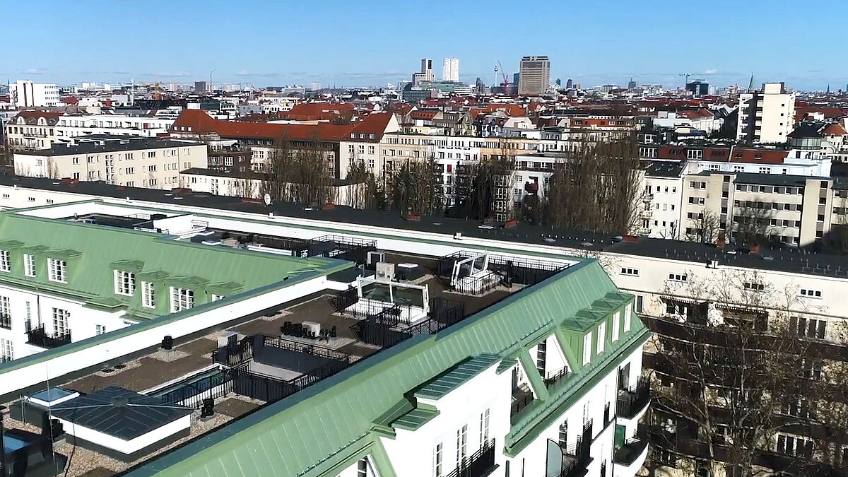 View of several LAMILUX flat roof hatches on a roof at Hochmeisterplatz in Berlin, surrounded by residential buildings and a city panorama.