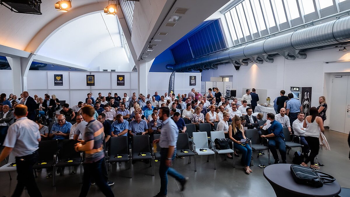 Interior view of the Vogel Convention Center in Würzburg with an assembly of attendees beneath modern glass roofs.