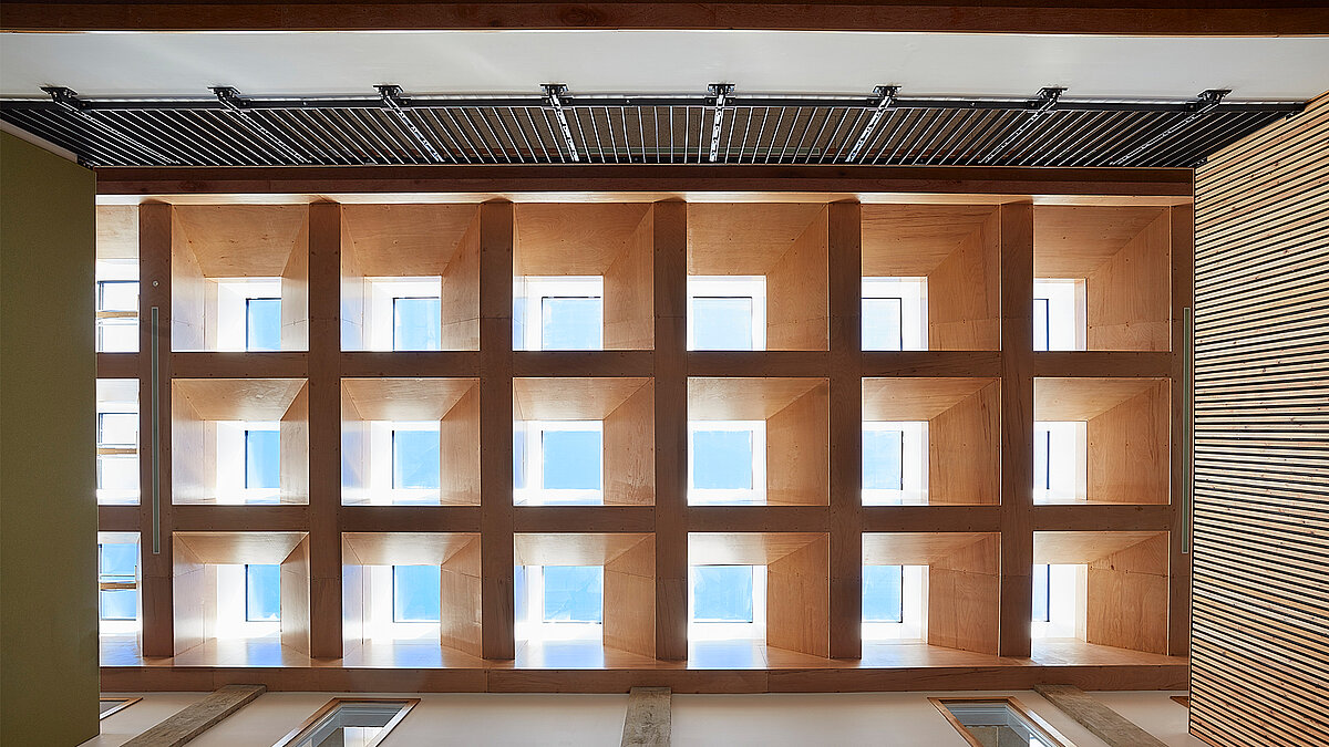 Modern wooden ceiling structure with square grid design and integrated window elements