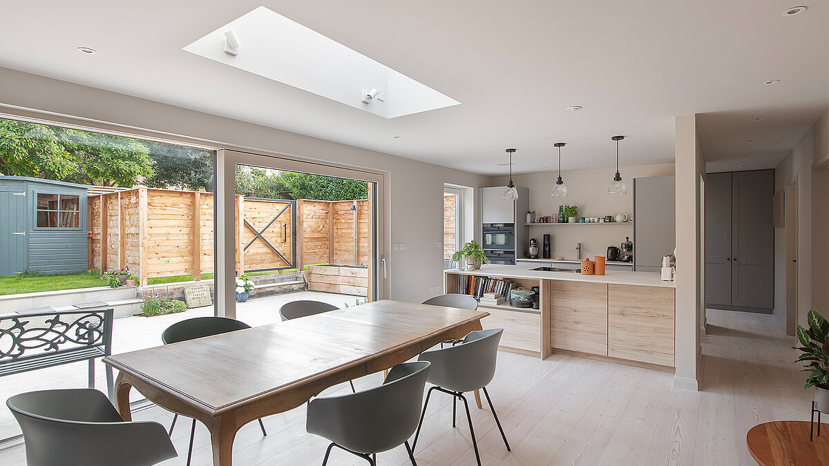 Open-plan living and dining area with LAMILUX flat roof window and large glass front