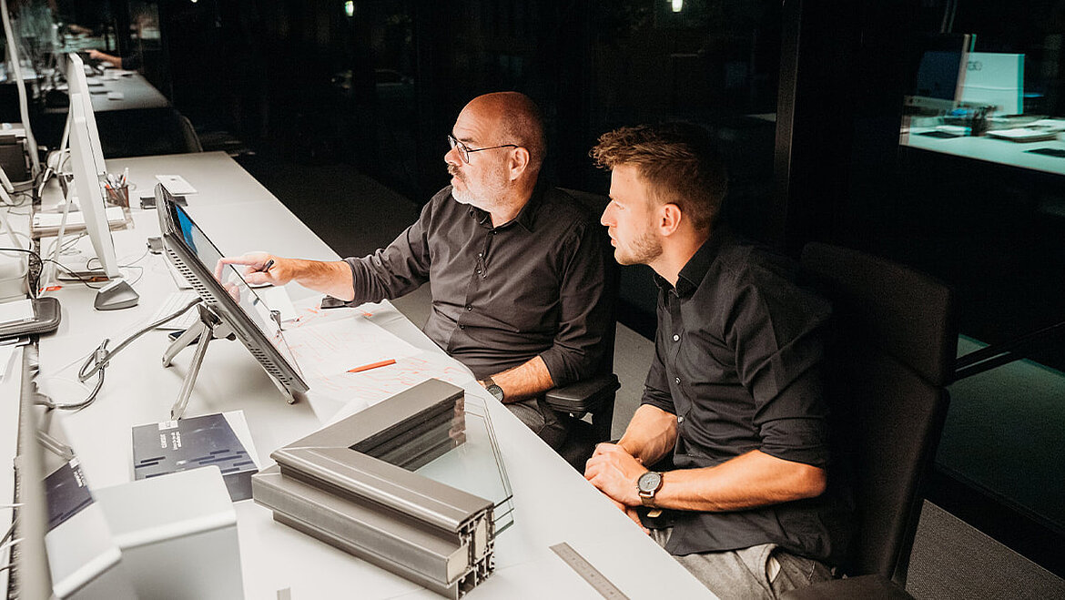 Zwei Fachplaner am Schreibtisch besprechen Baupläne am Computer