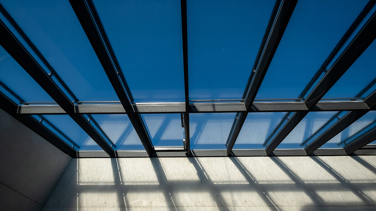 Detailed view of the glass roof of the Bertha-von-Suttner Realschule in Cologne with a clear view of the blue sky.
