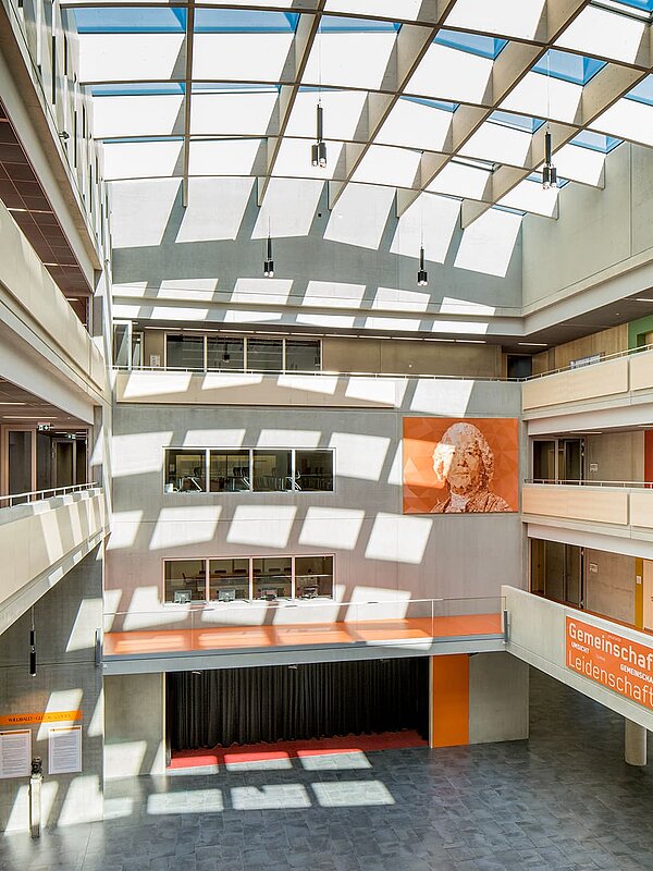 Interior view of the Willibald-Gluck-Gymnasium in Neumarkt with a large LAMILUX glass roof flooding the space with daylight.