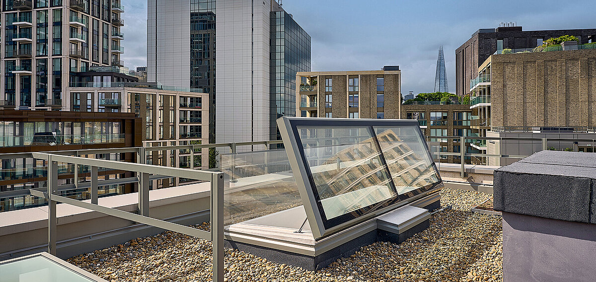 LAMILUX flat roof access on the rooftop of Mulberry Academy London, surrounded by gravel covering and modern architecture, with The Shard skyscraper visible in the background.