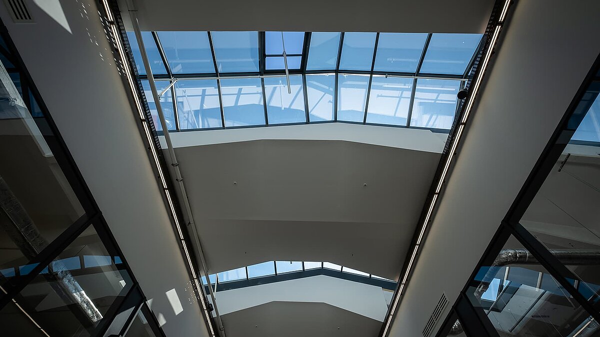 Interior view of the LAMILUX glass roof PR60 in the Outlet Centre Selb with blue sky and modern, light-flooded design.