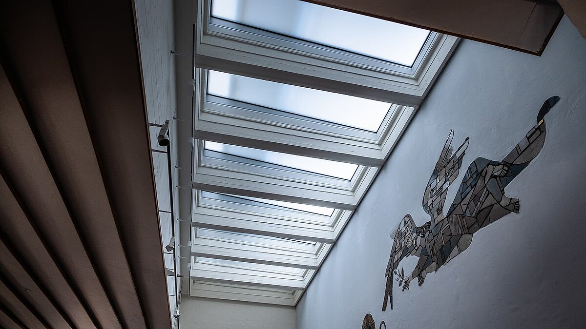 Interior view of St Paul's Church in Traunreut with LAMILUX FE flat roof windows and a large wall mosaic.