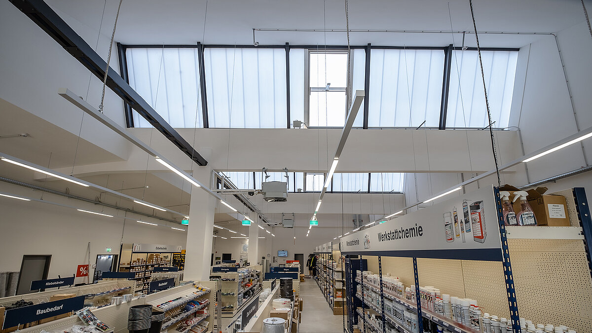 Renovated interior of the old post station in Leipzig, now used as a specialty store with daylight systems and tall glass roof windows.