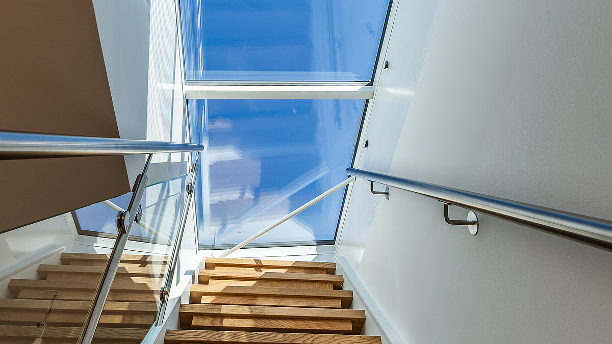 Staircase with flat roof access in a residential house in Korneuburg, modern glass roof with ample daylight.