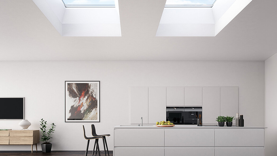 A minimalist white kitchen with two large skylights, a modern kitchen unit and a bright living area.