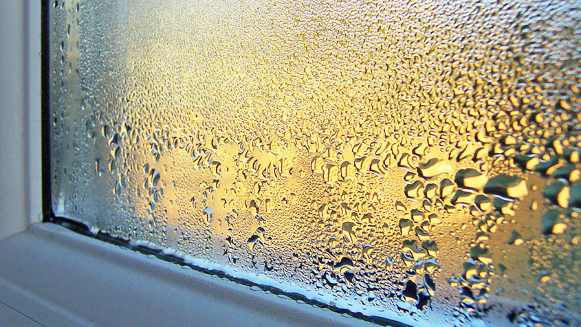 Kondenswasser an der Innenseite eines Fensters mit vielen Wassertropfen auf der Glasscheibe.