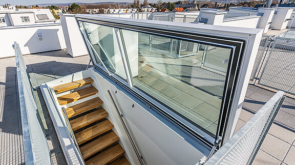Flat roof exit by LAMILUX at a residential house in Korneuburg, featuring a modern staircase and glazing with a view of the surroundings.