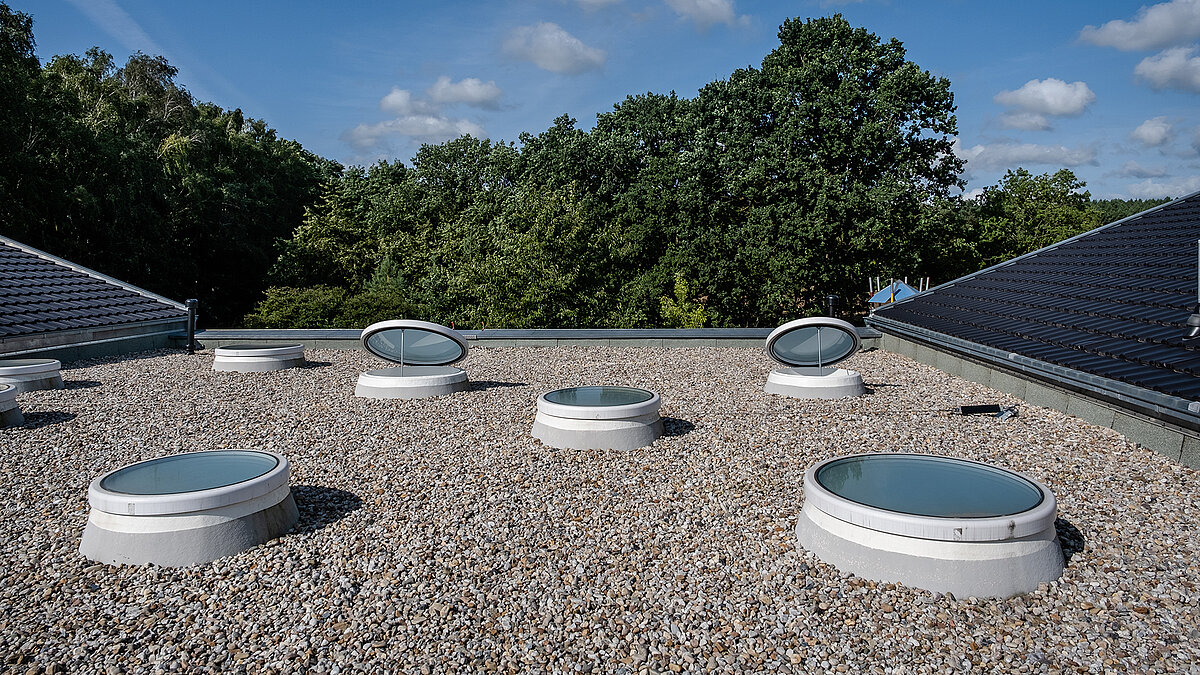 Round skylights on the gravel flat roof of the "Sonnenfeld" daycare center.