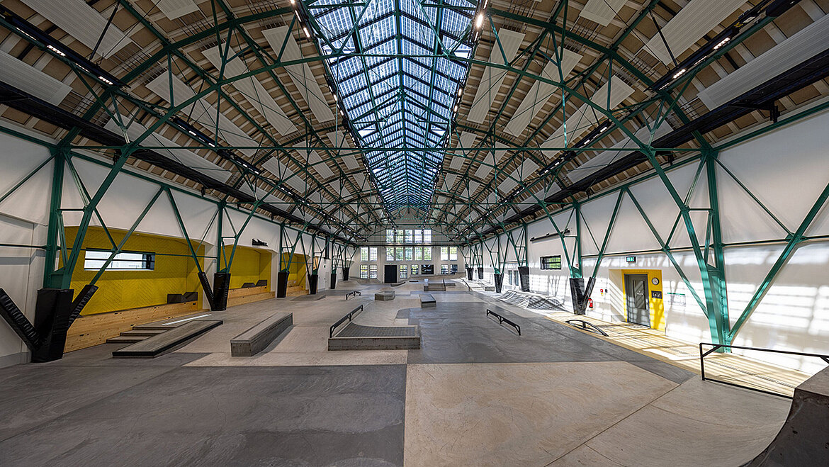 Skate hall with expansive steel structure and glass roof providing natural daylight illumination