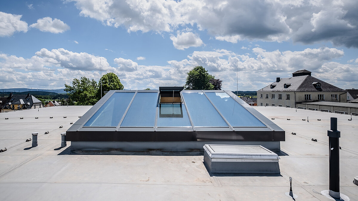 Large glass roof on a flat roof with a centrally positioned ventilation flap
