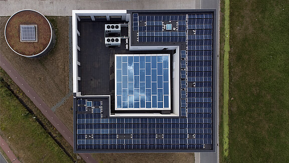 Aerial view of a flat roof with central glass roof and surrounding solar panels