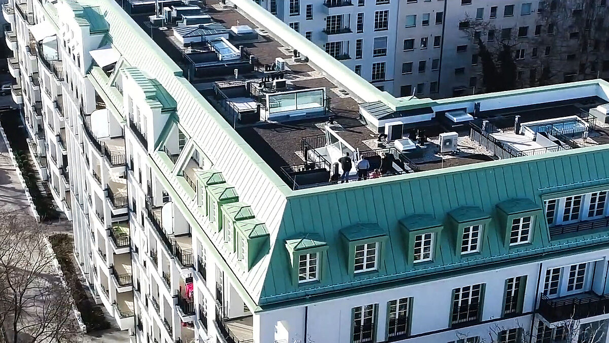 Drone view of a residential building at Hochmeisterplatz in Berlin featuring several LAMILUX flat roof accesses and green rooftop areas.